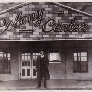 Man standing before building with sign "Colony Center"