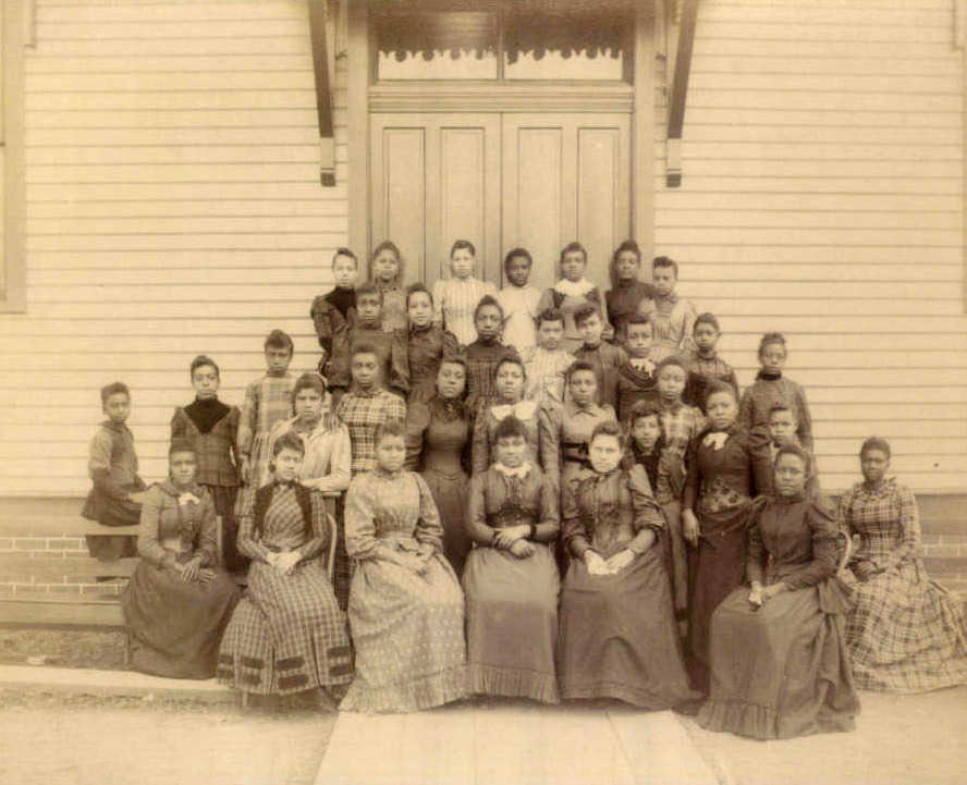 African American girls in dresses posted on steps of wooden building