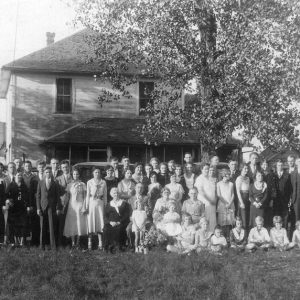 White men women and children outside two-story house