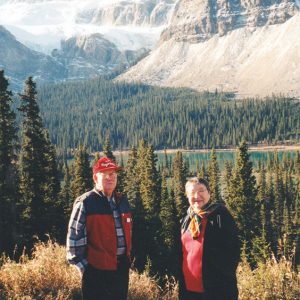 White man and white woman standing before mountains