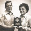 White man with glasses and white woman with glasses posing with award plaque