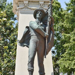 Statue of soldier with flag on stone monument