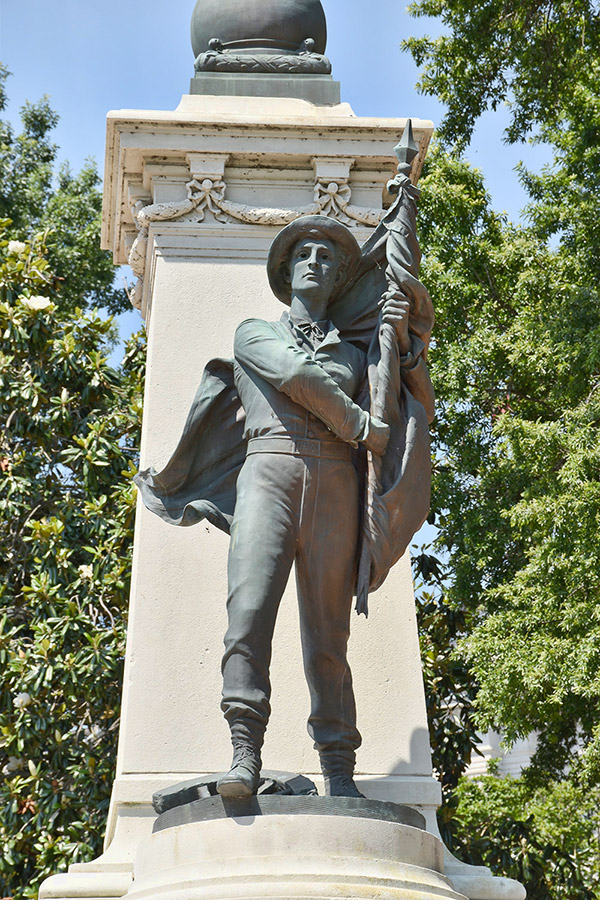 Statue of soldier with flag on stone monument