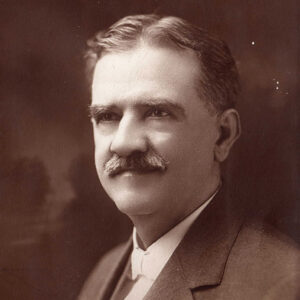 White man with mustache in suit and bow tie