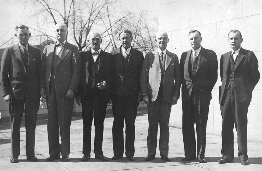 Group of older white men in suits standing together