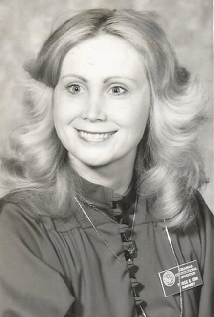 White woman smiling with long wavy hair and name tag