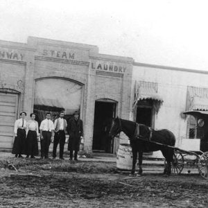 Three white men two white women and horse-drawn carriage outside brick laundry building