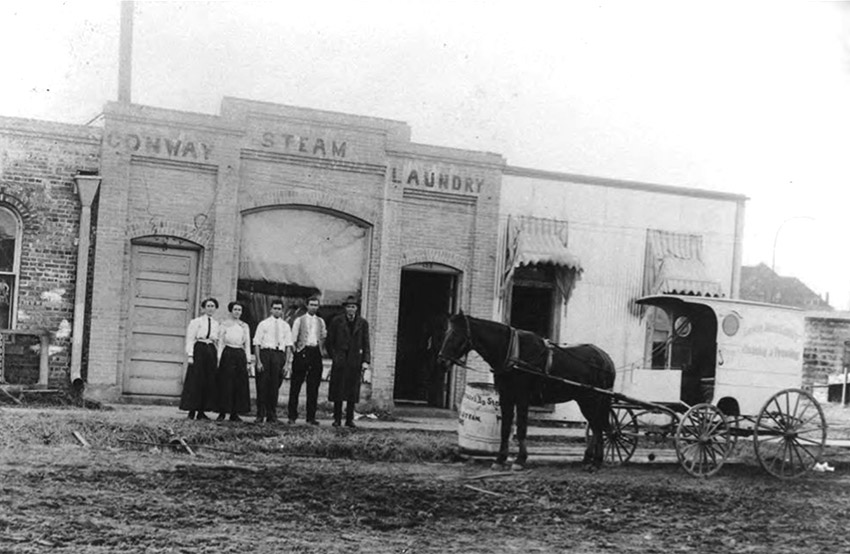 Three white men two white women and horse-drawn carriage outside brick laundry building