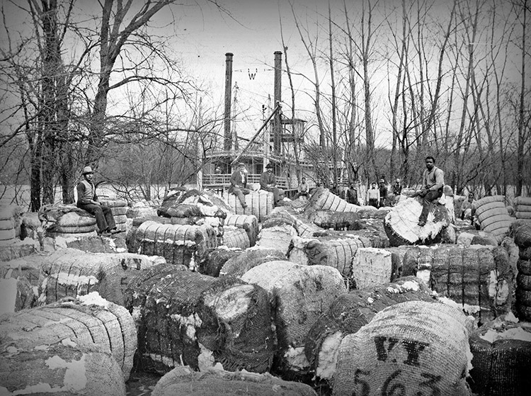 Cotton bales waiting to be loaded onto steamboat on river