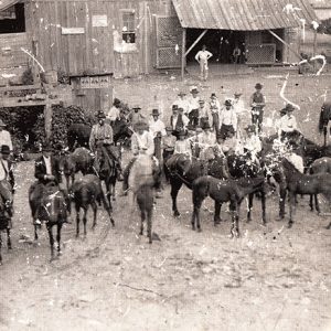 White men and horses with farm buildings around them