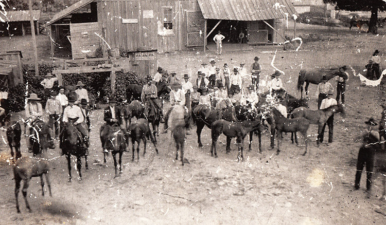 White men and horses with farm buildings around them