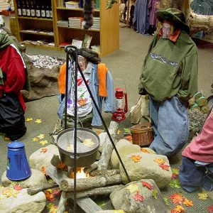Mannequins dressed like campers around a fake campfire indoors