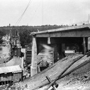 Construction site with two ends of concrete bridge and buildings