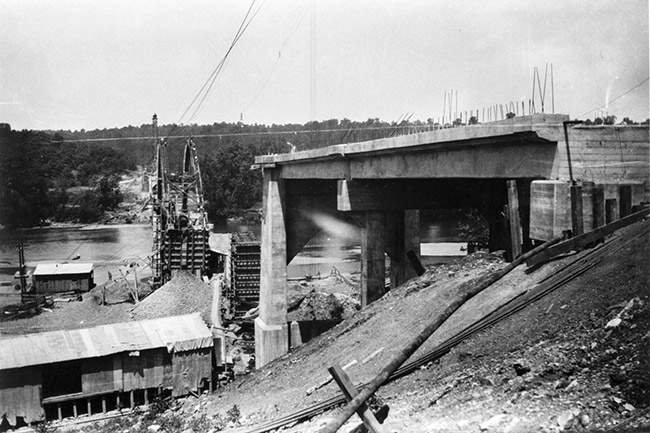 Construction site with two ends of concrete bridge and buildings