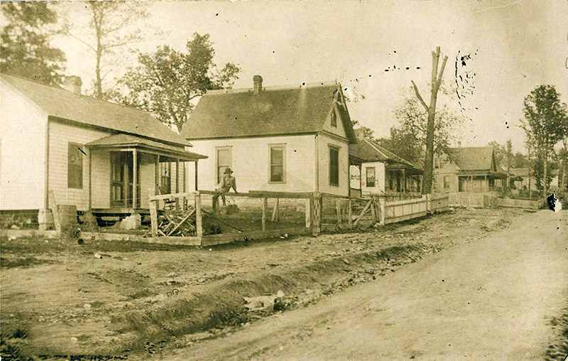 Single and multistory houses with covered porches on dirt road