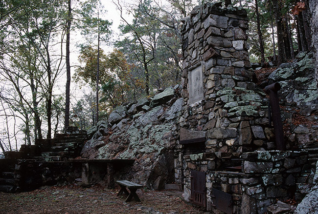 Stone chimney and other ruins in forested area