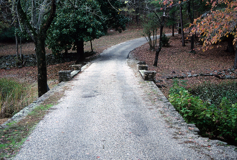 Paved road with small bridge amid forested area