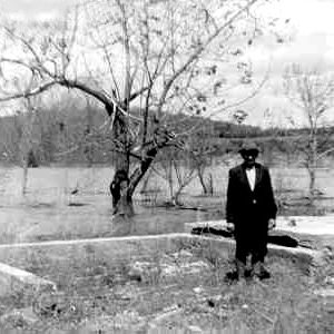 White man in suit standing in a flooded field