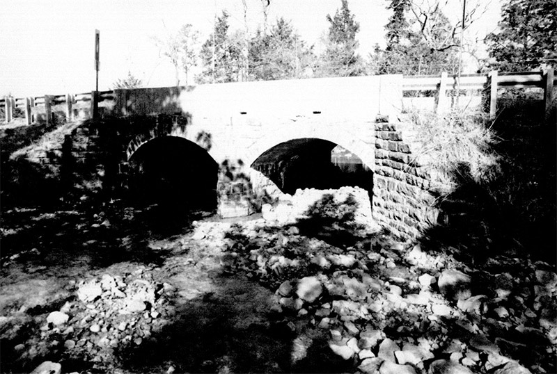 Side view of stone arch bridge over creek