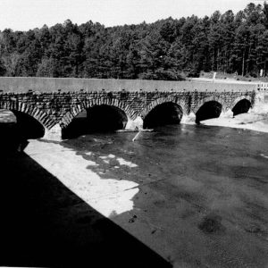 Brick arch spillway bridge with concrete platform and trees in the background