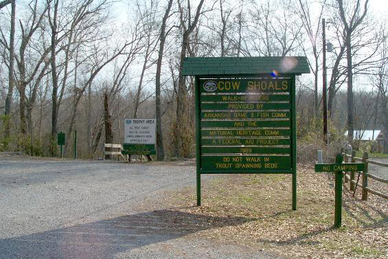 Road signs on gravel parking lot in wooded area