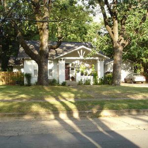 Single-story house with covered porch and trees on street