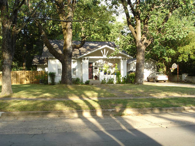 Single-story house with covered porch and trees on street