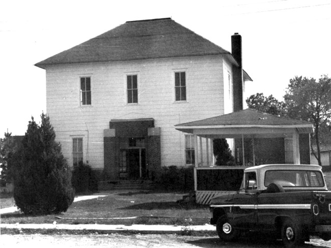 Two-story wooden building with gazebo and Chevrolet truck