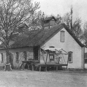 Single-story building with wood siding and two cupolas on its roof
