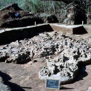 Excavation site with irregular pile of materials indicated by a small chalkboard