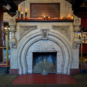 Ornate brick fireplace with peacock screen on red tiles