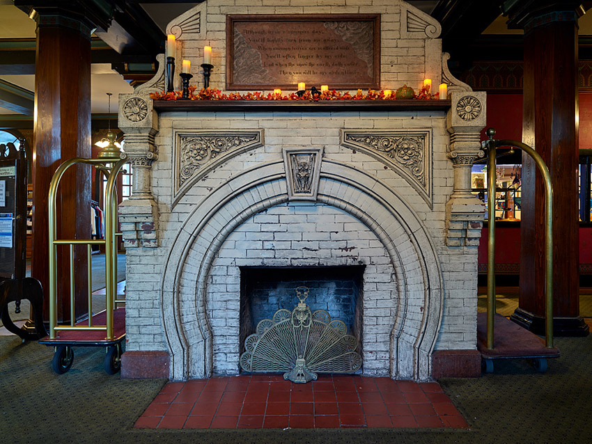 Ornate brick fireplace with peacock screen on red tiles