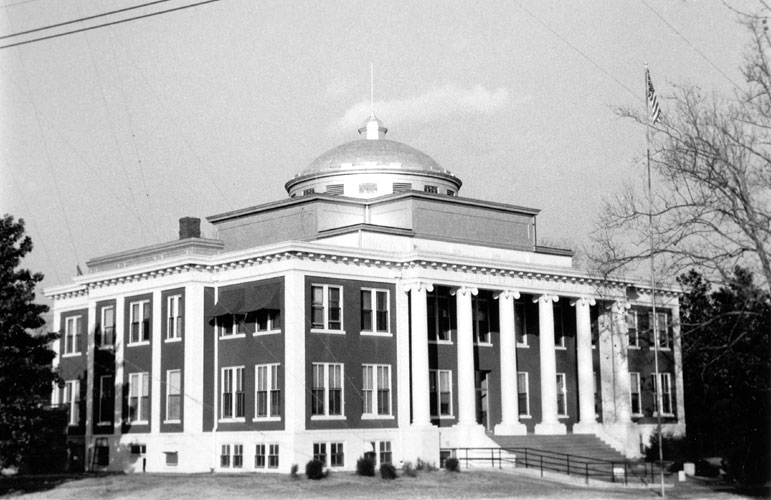 Three-story building with large round dome capped with a flagpole
