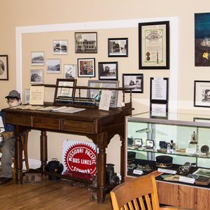 Interior museum with mannequin desk display case and photographs on the wall