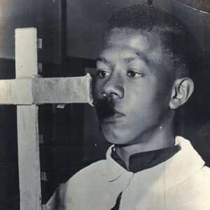 Young African American boy in robes with cross staff
