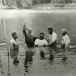 Group of African-American men performing a baptism outdoors