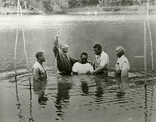 Group of African-American men performing a baptism outdoors