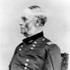 Profile view of white man with sideburns in military uniform sitting in a chair