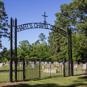 Cemetery inside fence with iron arch with cross on it and gate