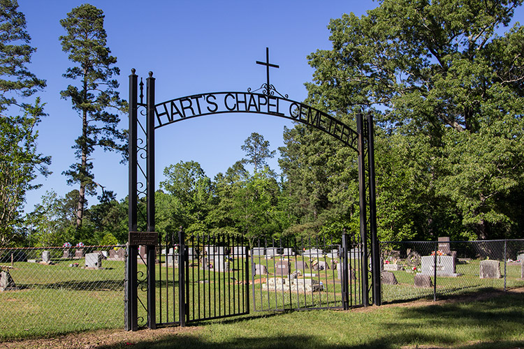 Cemetery inside fence with iron arch with cross on it and gate