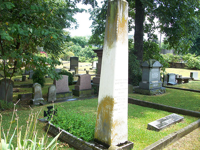 Weathered obelisk shaped gravestone in cemetery