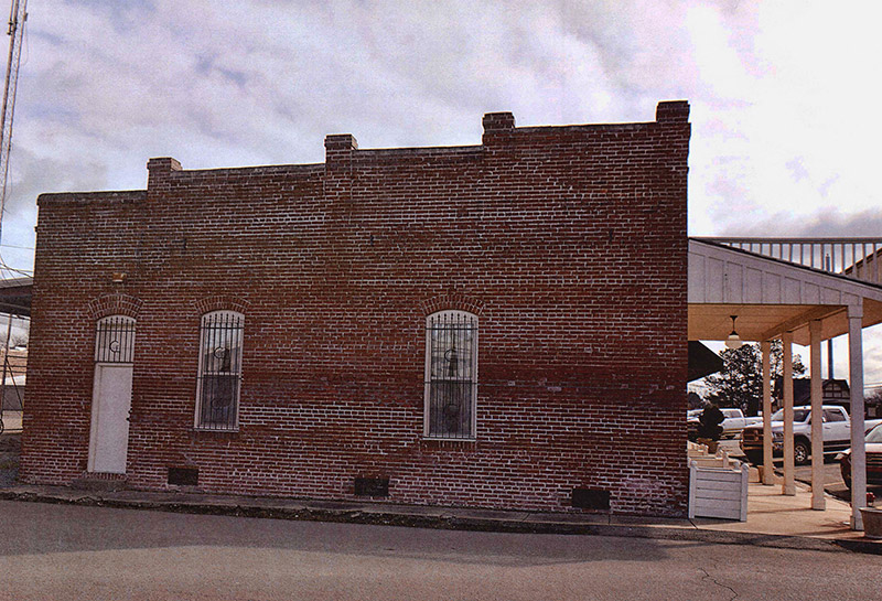 Side view of brick storefront with covered entrance and balcony