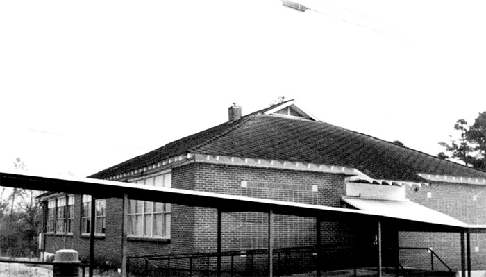 Brick school building with gabled roof and covered walk way