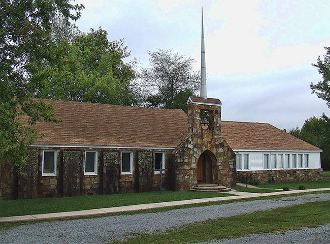 Single-story building with arched stone entry way and tall spire