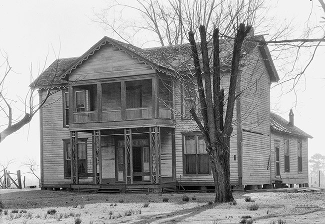 Two-story house with covered porch and bare trees