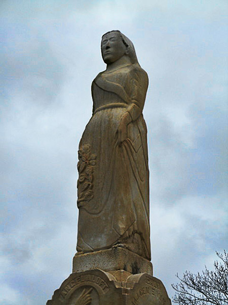 Statue of woman on grave marker with blue sky