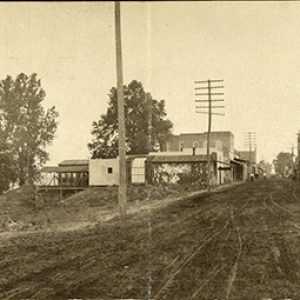 Two-story brick buildings and power lines on dirt road
