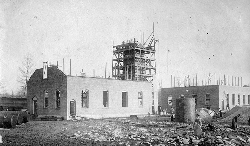 Brick building under construction with scaffolding on tower