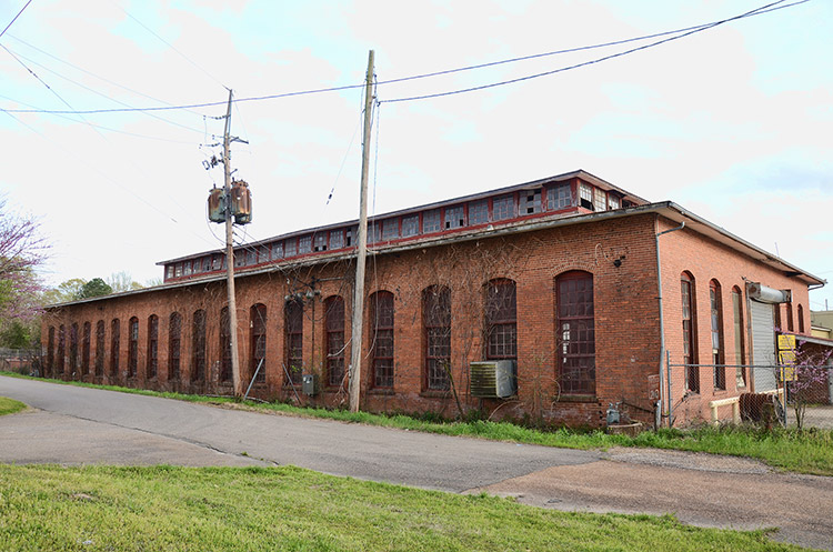 Brick building with tall arched windows and power lines on street