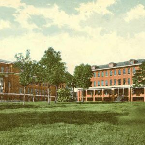Multistory brick campus buildings on grass with trees